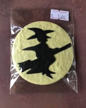 Die cuts of a black witch on a broom surrounded by a whilte moon circle.