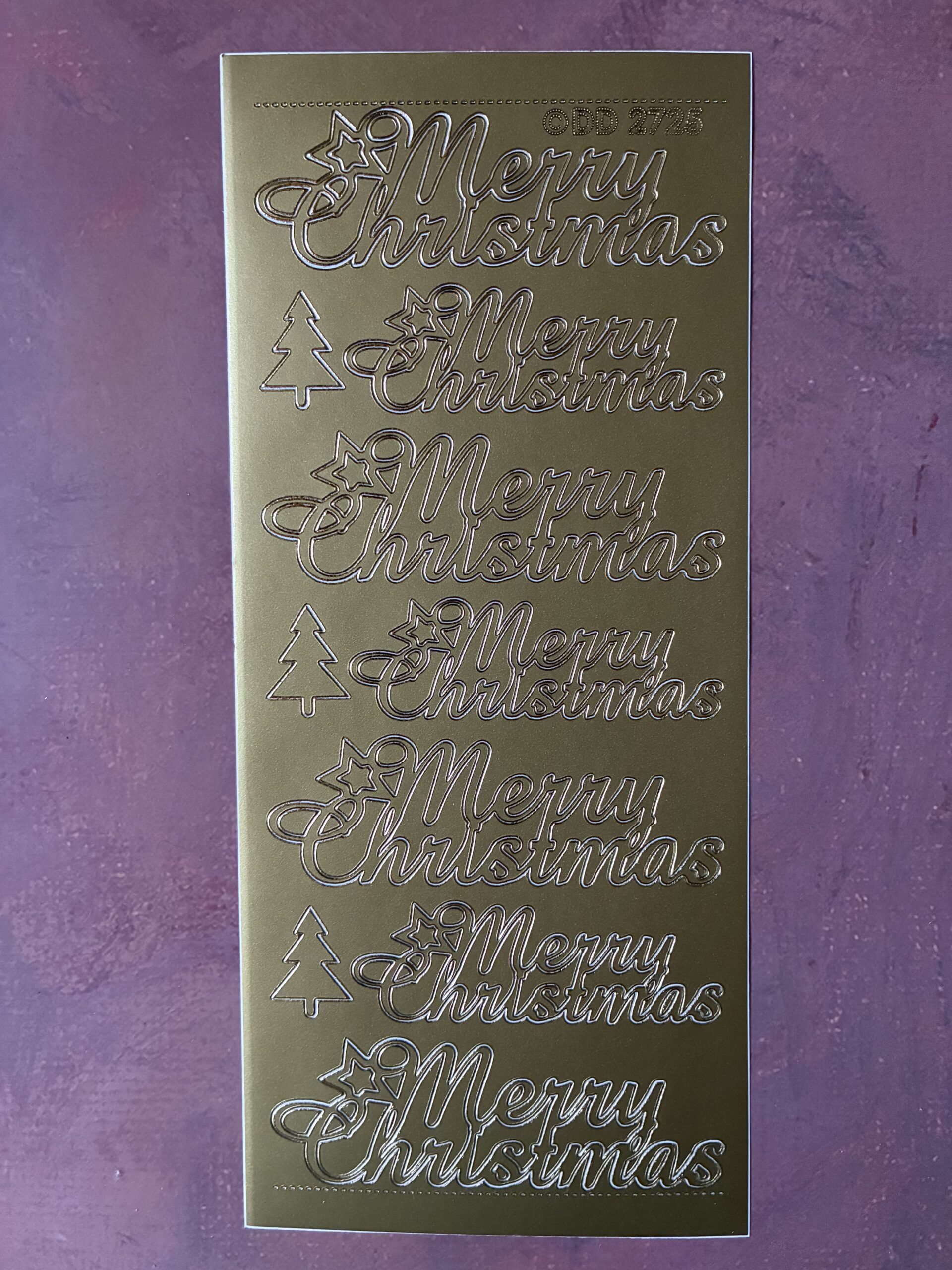 This sheet of festive sentiment peel off stickers features seven large 'Merry Christmas' words and three additional trees in a gold colour.
