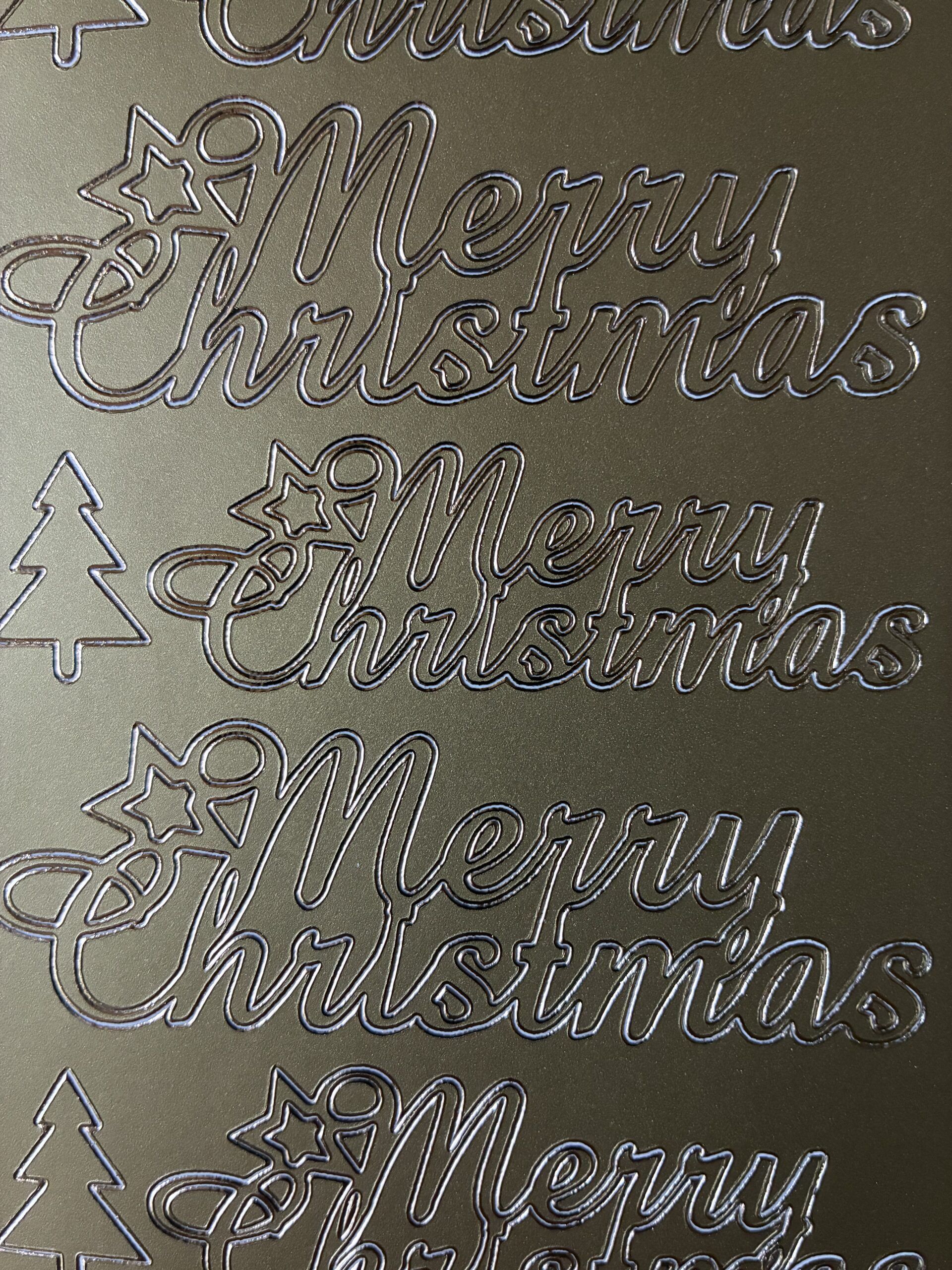 This sheet of festive sentiment peel off stickers features seven large 'Merry Christmas' words and three additional trees in a gold colour.